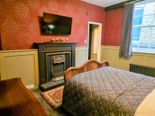 a bedroom with a bed and a fireplace and a television at The New Inn by Roomsbooked in Gloucester