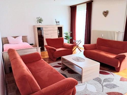 a living room with red furniture and a bed at RJS Lambach GbR, Ferienwohnung am Dorfplatz in Waldkappel