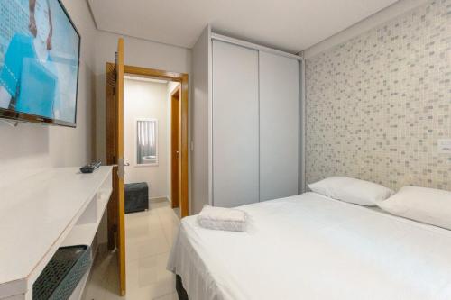 a small bedroom with a white bed and a mirror at Aproveite este achado! - GC1108 in Maringá