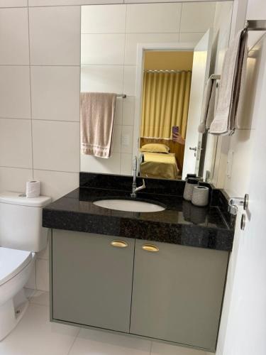 a bathroom with a sink and a toilet and a mirror at Luxo e Lazer Apto 2Qtos 1 Suíte AC e Rooftop in Belém