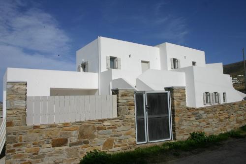 un grand bâtiment blanc au sommet d'un mur de pierre dans l'établissement Persephone's Summer House Paros - 2BR Garden Villa, à Parasporos