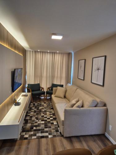 a living room with a couch and a tv at Luxo e Lazer Apto 2Qtos 1 Suíte AC e Rooftop in Belém