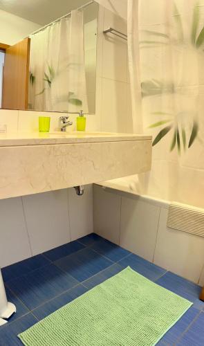 a bathroom with a sink and a mirror and a green rug at Vista Dourada in Porto Santo