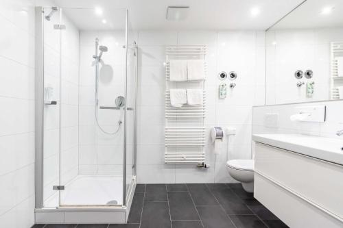a white bathroom with a shower and a toilet at Hotel Wandinger Hof in Markt Schwaben
