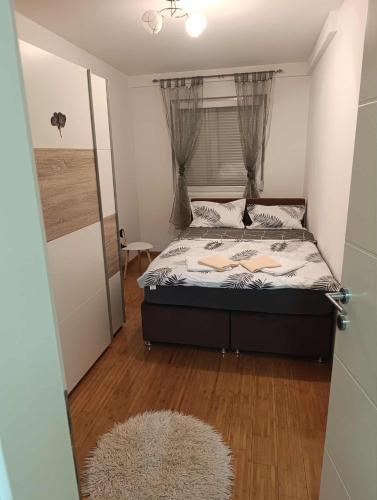 a bedroom with a bed with a window and a rug at Apartman Čakarević in Doboj