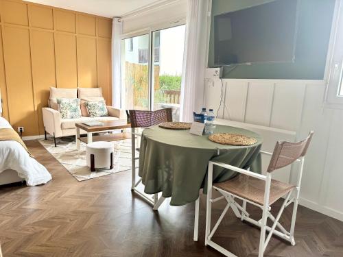 ein Wohnzimmer mit Tisch und Stühlen und einer Couch in der Unterkunft Studio La Petite Oasis - idéal couple - lumineux - calme - 10min à pieds du centre ville & de la plage - balcon exposé sud - 2km du Centre Juno Beach - stationnement & wifi gratuits in Courseulles-sur-Mer