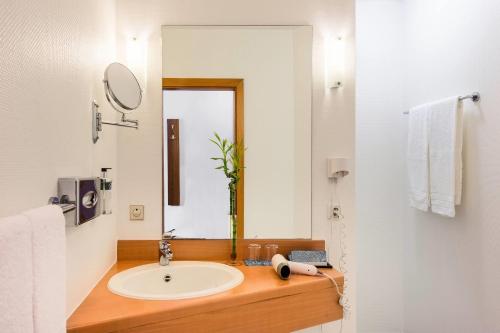 une salle de bain avec un lavabo et un miroir dans l'établissement Hotel Bochum Wattenscheid affiliated by Meliá, à Bochum
