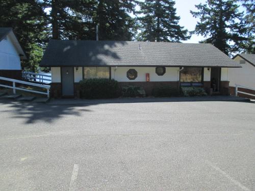 Woahink Lake Suites في Dunes City: مبنى ابيض بسقف اسود وموقف سيارات