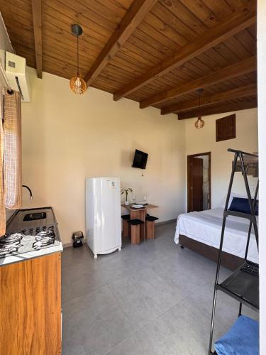 a kitchen with a refrigerator and a bed in a room at Pousada Tudix in Praia do Rosa