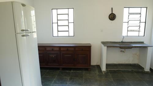 a kitchen with a sink and two windows at Canto das Árvores - Nova União MG in União de Caeté