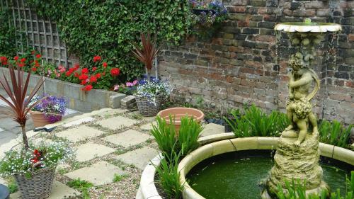 a fountain in a garden with plants and flowers at Jessamine House Hotel in Gravesend