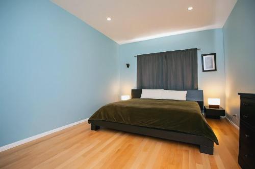 ロサンゼルスにあるModern 2 Bedroom Condo near Abbot Kinneyの青い壁とウッドフロアのベッドルーム1室