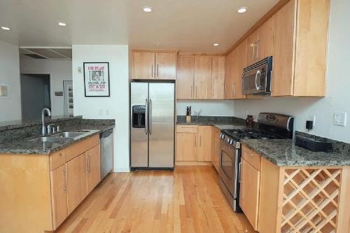 ロサンゼルスにあるModern 2 Bedroom Condo near Abbot Kinneyのキッチン(木製キャビネット、ステンレス製の冷蔵庫付)