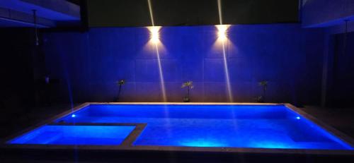 a blue swimming pool with lights on the wall at Pousada Coisa Nossa in Itanhaém