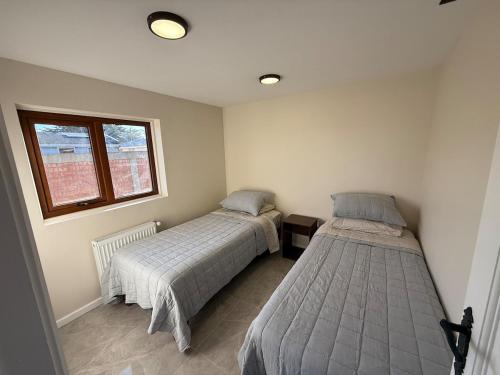 deux lits dans une petite pièce avec une fenêtre dans l'établissement Casa cerca costanera central, à Punta Arenas