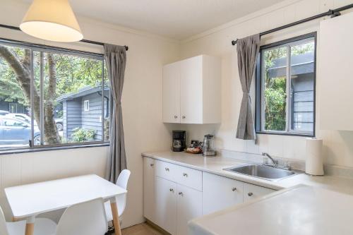 eine Küche mit weißen Schränken und einer Spüle und einem Fenster in der Unterkunft Mackenzie Beach Resort in Tofino