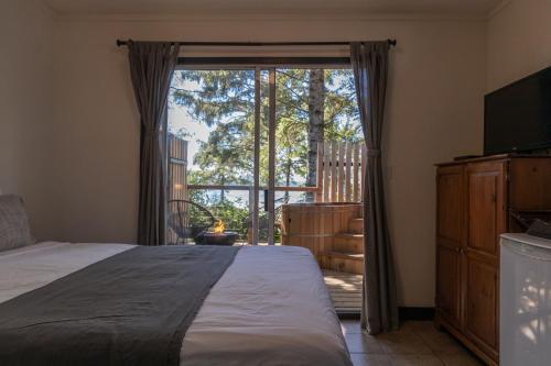 a bedroom with a bed and a large window at Mackenzie Beach Resort in Tofino