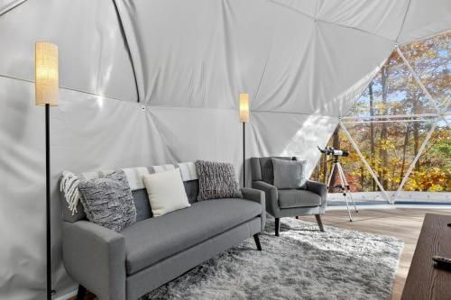 een woonkamer met een bank en twee stoelen in een tent bij Glamping Dome w Fire Pit WiFi King Bed & Bath in Wardensville