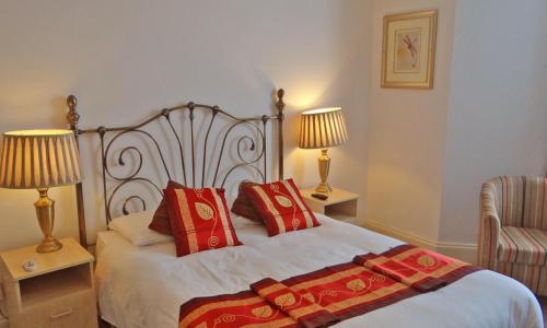 a bedroom with a bed with red pillows and two lamps at Jessamine House Hotel in Gravesend