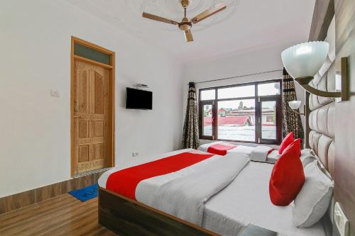 a bedroom with a bed with red pillows and a window at Hotel O Hameed in Durgjan