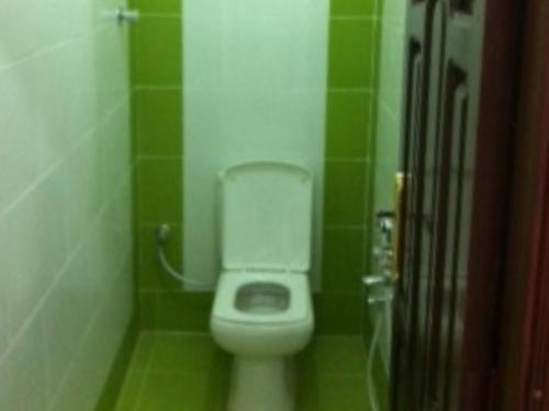 a bathroom with a toilet in a green tiled room at السعادة للشقق المفروشة 