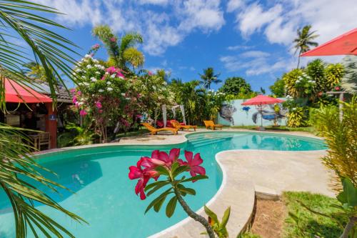ein Swimmingpool in einem Ferienresort mit einer rosa Blume in der Unterkunft Xainã Pousada de Charme in Cumbuco