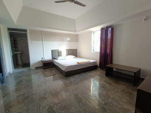 a bedroom with a bed and a table in it at Saagar's Farmstay in Jalpāiguri