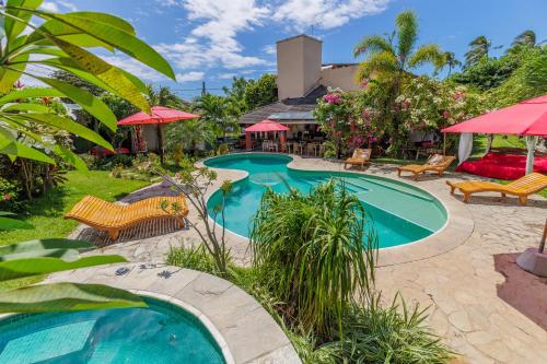 a swimming pool in a yard with chairs and umbrellas at Xainã Pousada de Charme in Cumbuco