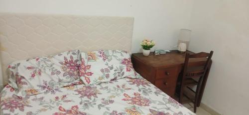 a bedroom with a bed and a desk with a floweridered pillow at Alojamiento Edificio Alicante ll in Asunción