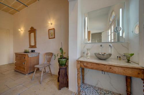 a bathroom with a sink and a mirror and a chair at Villa Josette with Pool Table and Garden by Haven and Keys Malta in Tal-Għoqod