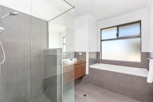 a bathroom with a shower and a tub and a sink at Coastal Retreat in Burns Beach in Kinross