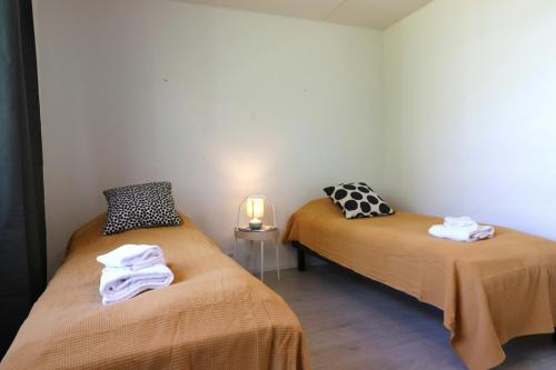 a room with two beds and a lamp on a table at Central and Spacious Apartment for 4 with Sauna in Kirkkonummi