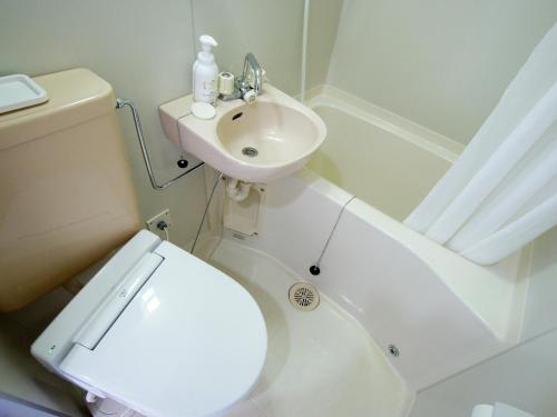 a white bathroom with a toilet and a sink at Hotel Trend Nagano in Nagano