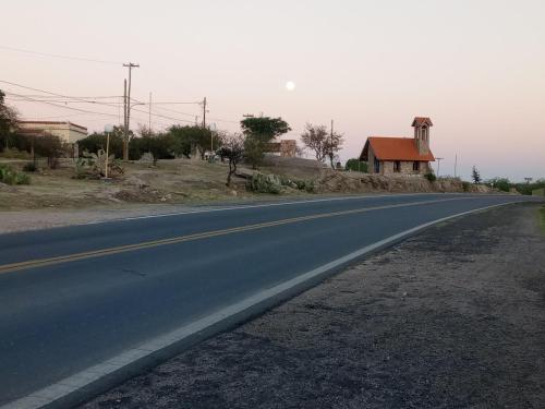 een lege weg met een huis in de verte bij Los patos in Capilla del Monte