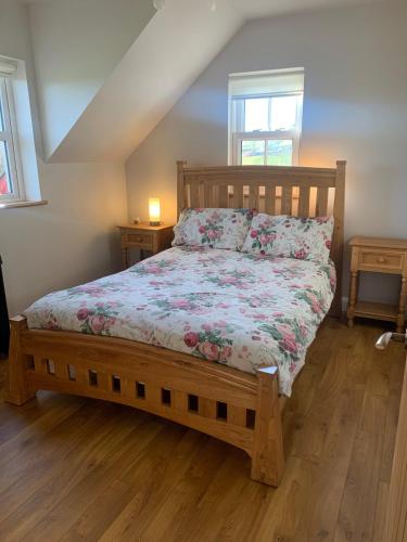 a bedroom with a wooden bed with a floral bedspread at Paul's country cottage in Donegal
