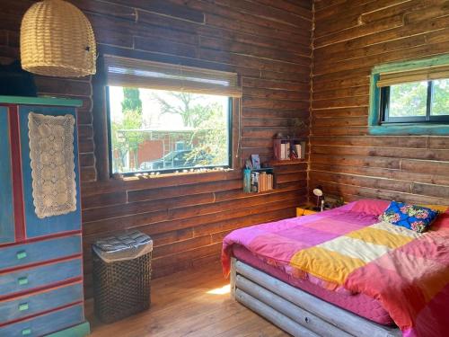 ein Schlafzimmer mit einem Bett in einem Holzzimmer in der Unterkunft Cabaña frente al lago in La Estancia