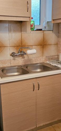 a kitchen with a stainless steel sink and wooden cabinets at Castle Balcony in Nafpaktos