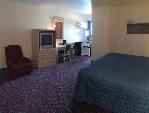a hotel room with a bed and a desk and a television at Cedar Motor Inn in Marquette