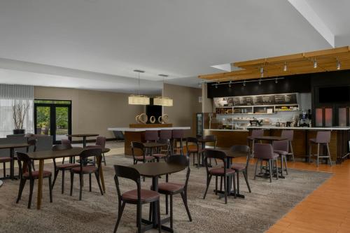a dining room with tables and chairs and a kitchen at Courtyard Charlotte Airport North in Charlotte