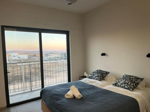 a bedroom with two beds and a large window at צימר בלב הגולן קצרין in Qasrîne