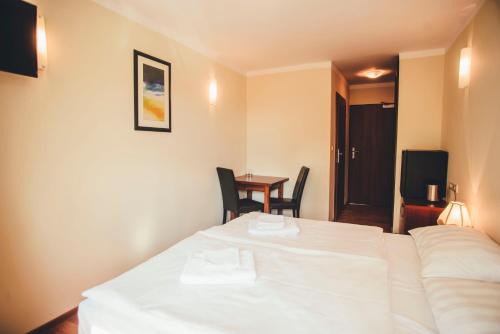 a hotel room with a white bed and a table at Hotel Trojan in Lądek-Zdrój
