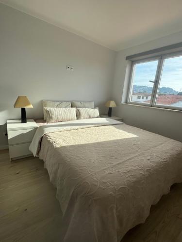 a white bedroom with a large bed and a window at Sunset Paradise in Caminha