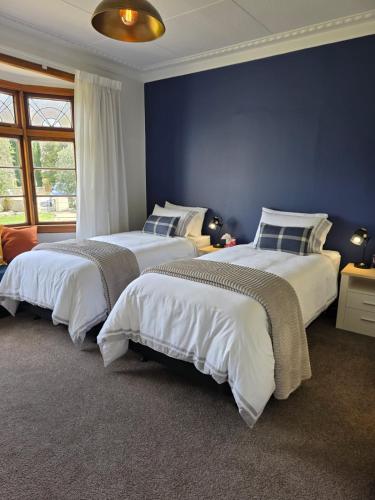 a bedroom with two beds and a blue wall at Clyde on Sunderland in Clyde
