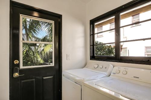 a white laundry room with a black door and window at West Beach Villa 3 in Santa Barbara