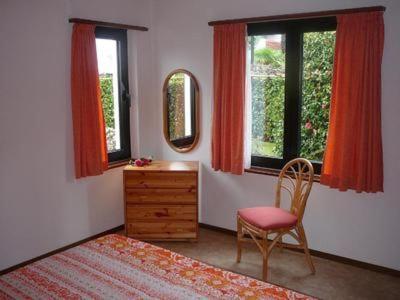a bedroom with a chair and a dresser and two windows at Casa Adelizia in Ascona
