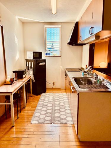 a kitchen with a sink and a table in it at バス停"平城札所前"徒歩0分 四国愛媛の宿 "40番たっきゅうミニホテル" "No40 Takkyu mini hotel" in Hirajō