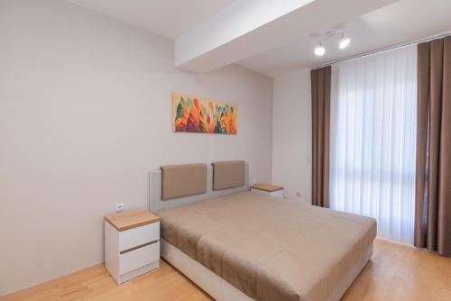 a bedroom with a bed and a painting on the wall at Aria Pearl Apartment in Bitola