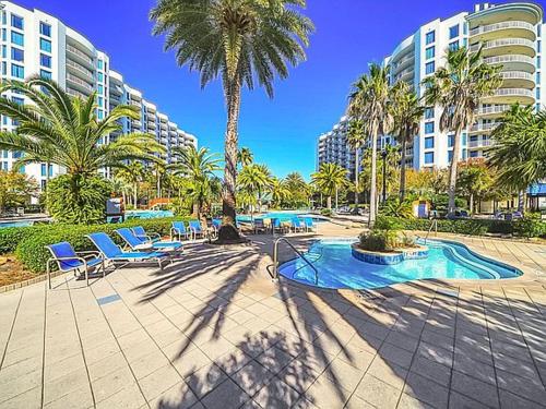 un resort con sedie, palme e piscina di 5 Star Resort 6th fl 2BR 2 BATH King Suite Shuttle Pools Family a Destin
