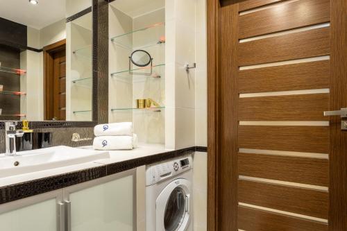 une salle de bains avec lave-linge et lavabo dans l'établissement Urban Chic - One Bedroom Apartment -Luxury Warsaw Stays - Grzybowska 5, à Varsovie