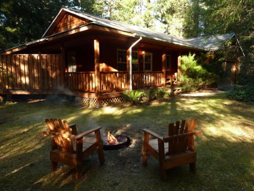 a log cabin with two chairs and a fire in the yard at Almost Paradise Lodging in Ashford